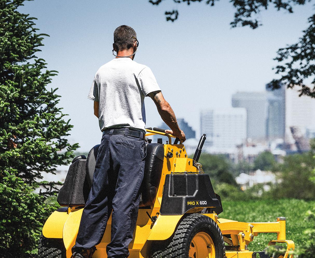 Man standing on a Cub Cadet Stand On Mower